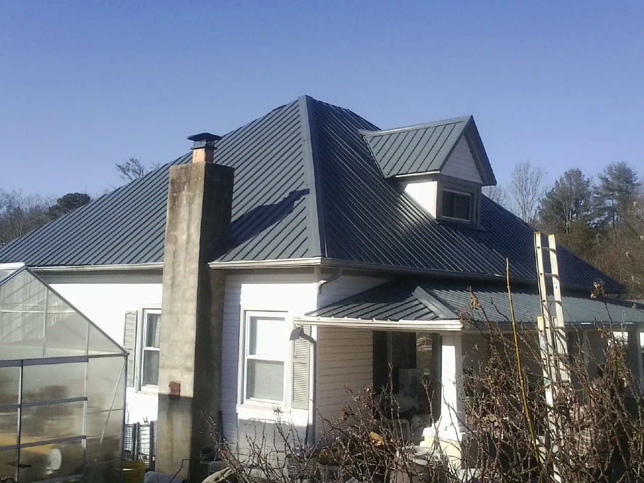Dark blue standing seam metal roof on a white farmhouse with dormer — Slate & Tile Roof Repair by Roofing Brothers in Spring Mills