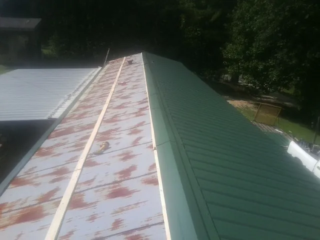 Old rusted panels beside newly installed green metal roofing — Wind Damage Roof Repair by Roofing Brothers in Spring Mills