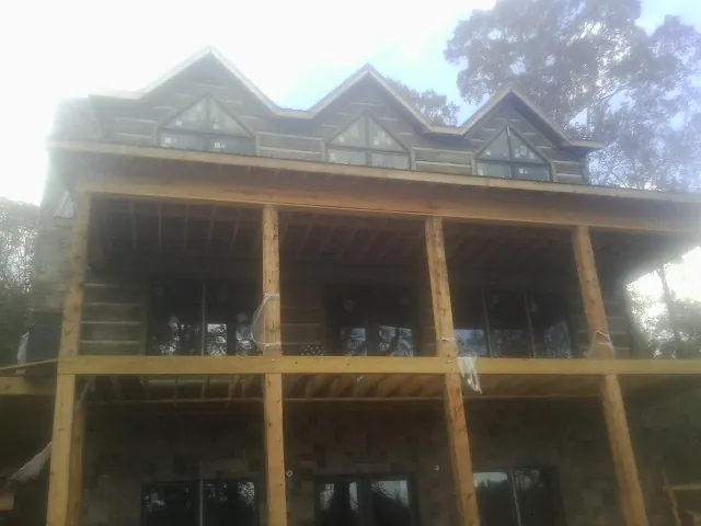 Dormers and porch framing on a large log home under construction — Roof Coating work by our crew in Spring Mills