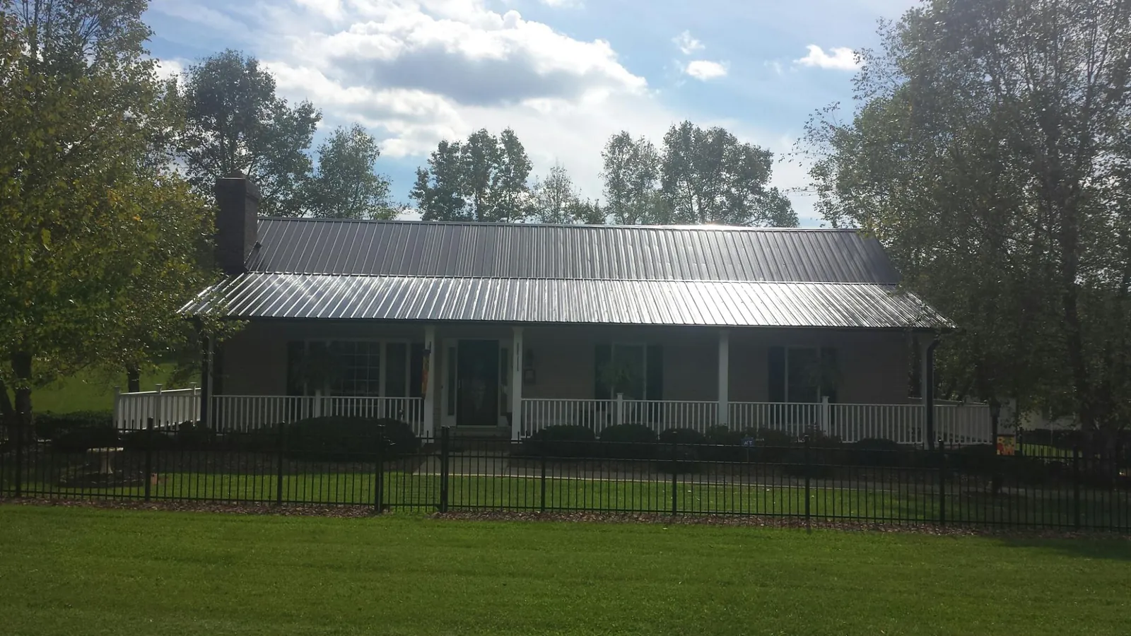 Gray metal roof on a brick ranch with a full width front porch — Gutter Guard Installation work by our crew in Spring Mills
