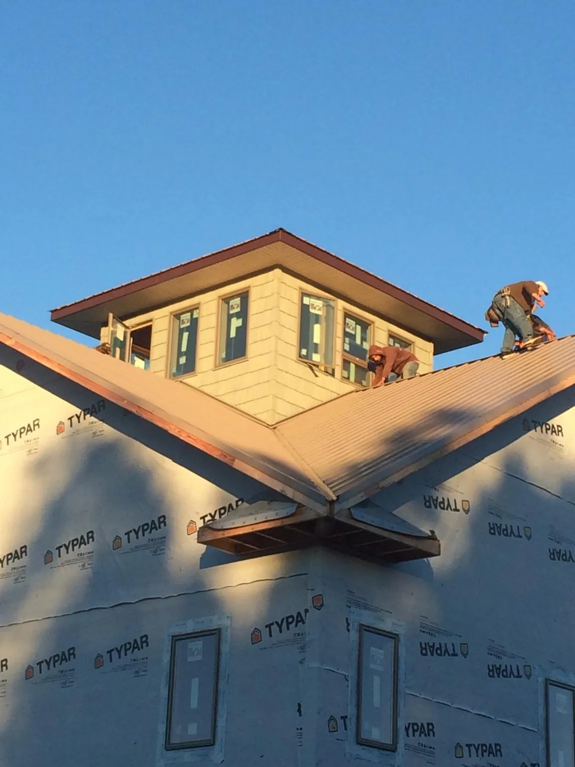 Roofers working around a rooftop cupola on a new metal roof at sunset — Roof Waterproofing in Spring Mills by Roofing Brothers